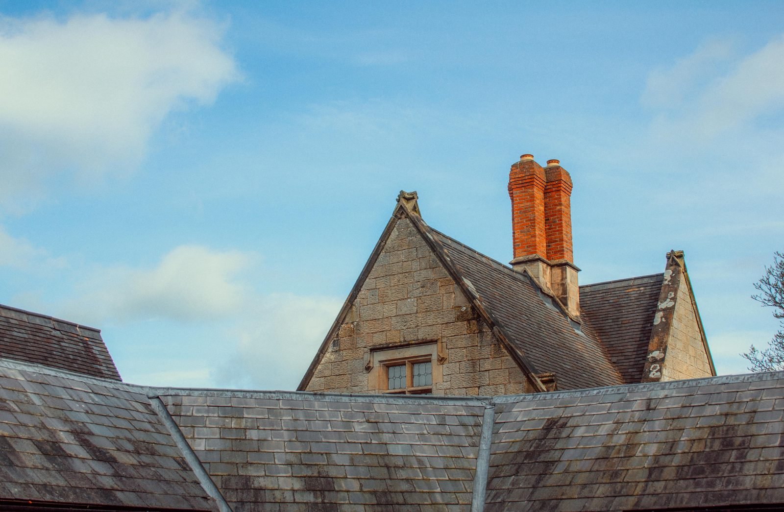 Stone gable with brick chimneys and slate roofline